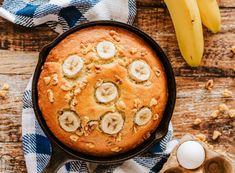 a cake with bananas and nuts in it on top of a table next to an egg