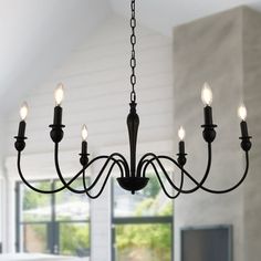 a black chandelier hanging from a ceiling in a room with white walls and windows