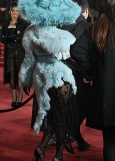 a woman in a blue furry animal suit and black heels is walking down the red carpet