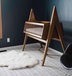 a baby crib next to a black chair and white rug in a room with blue walls