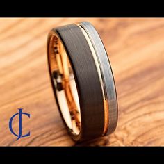 two tone gold and black ceramic wedding ring on wooden background with the word, d