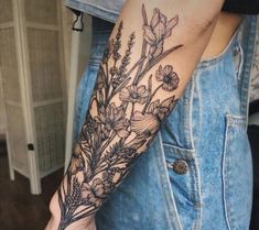 a woman's arm with flowers and leaves tattooed on the left side of her arm