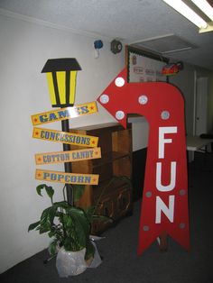 a large red arrow shaped sign sitting next to a potted plant and wooden boxes