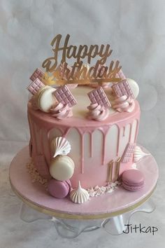 a pink and white birthday cake with seashells on it