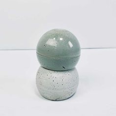 a gray and white ceramic container sitting on top of each other in front of a white wall