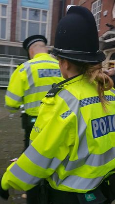 two police officers walking down the street in bright yellow jackets with their backs turned to the camera