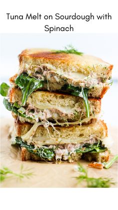 three sandwiches stacked on top of each other with meat and vegetables in the middle, sitting on a cutting board