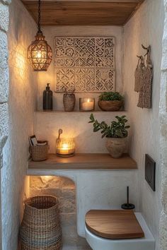 a bathroom with a toilet and some plants on the shelf next to it, lit by candles