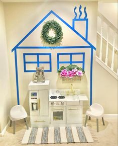 a play kitchen in the shape of a house with blue trim and flowers on top