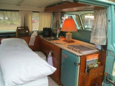 the interior of an old camper van with a bed in it and a lamp on