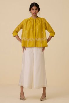 An exquisite top crafted from handwoven chanderi. Finely hand embroidered in our studio. Slim band collar and concealed placket. Delicate gathering around the neckline. 3/4 length sleeves. Two-button fastening cuff. Slip included.Note: Slight differences in embroidery speak to the hand processes involved. Garment Measurements in Inches : XS S M L XL Bust 47 49 51 53 55 Hip 56 58 60 62 64 Length 24.5 24.75 25 25.25 25.5