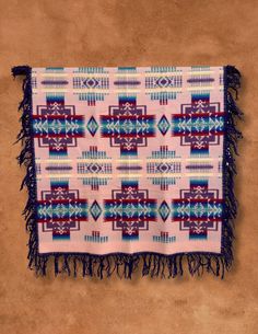 a blanket with fringes on it sitting on the floor in front of a wall