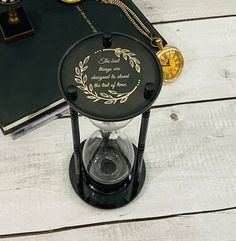 a black and gold clock sitting on top of a wooden table next to a book