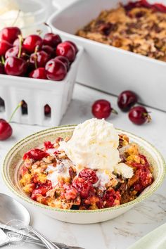 a bowl filled with ice cream and cherries next to a dish full of baked goods