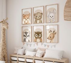 a nursery room with several pictures on the wall and stuffed animals hanging above it, including a giraffe