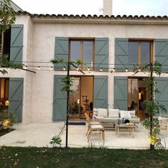 an outdoor patio with chairs and tables in front of a large building that has blue shutters