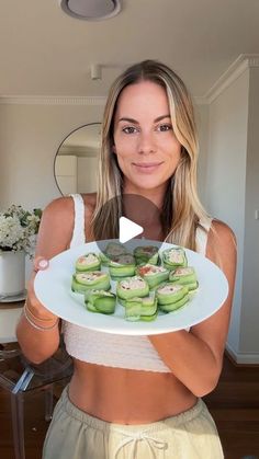 a woman holding a plate with cucumbers on it