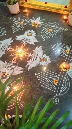 a decorated floor with lit candles and flowers in the center, surrounded by potted plants