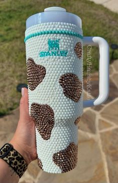 a person holding up a coffee cup with hearts on the outside and inside, while wearing leopard print bracelets