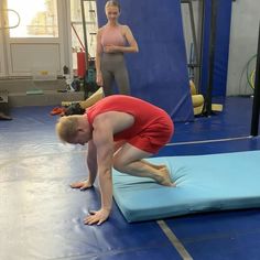 a man and woman doing yoga exercises on mats in a room with blue flooring