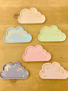 four pastel clouds are sitting on a wooden surface with gold flecks in them