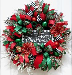 a christmas wreath with red and green bows on the front door that says merry christmas