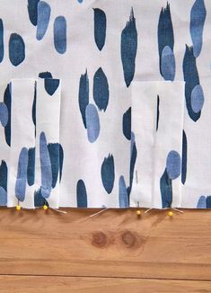 three pieces of fabric with blue and white spots on them sitting on a wooden surface