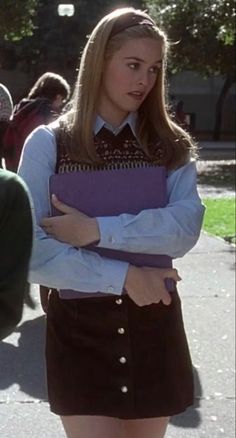 two young women standing next to each other in the street, one holding a binder