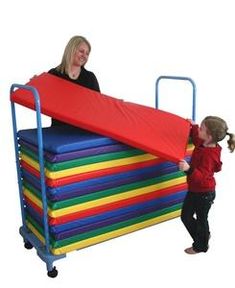 a woman standing next to a child on top of a large stack of colorful blocks