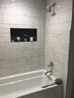 a white bath tub sitting inside of a bathroom next to a shower faucet