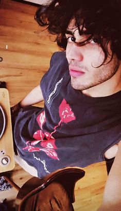 a man with long hair laying on the floor next to an old stereo and record player