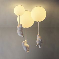 three white lamps hanging from the ceiling with bears and balls attached to each lamp fixture