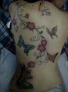 the back of a woman's body with butterflies and flowers on her side,