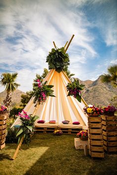 a teepee is set up with flowers and greenery