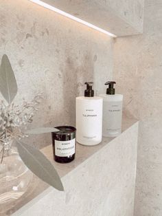 a bathroom counter topped with two bottles and a vase filled with flowers