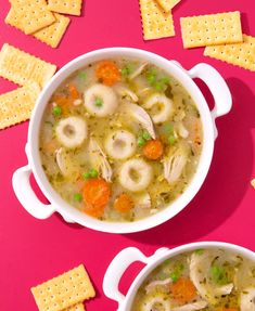 two bowls filled with soup and crackers on a pink surface next to each other