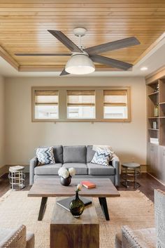 a living room with a couch, coffee table and ceiling fan in the middle of it