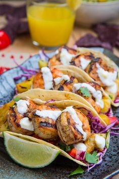 three tacos with shrimp, lettuce and sour cream on them sitting on a plate