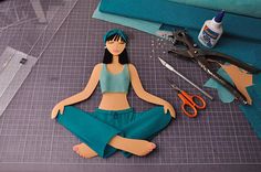 a paper doll sitting on top of a table next to scissors and other crafting supplies