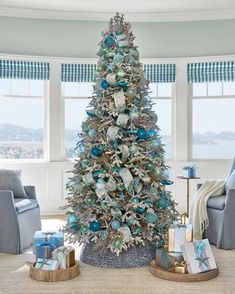 a decorated christmas tree in a living room with blue and silver decorations on the top