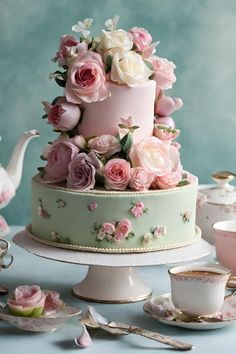 there is a cake with pink flowers on it and teacups next to it