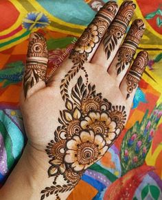 a woman's hand with hennap on top of colorful fabric and flowers