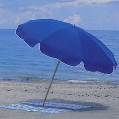 an umbrella is on the beach near the water