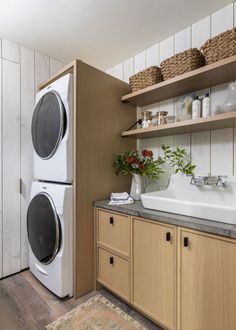 a washer and dryer in a small room with wooden shelves on the wall