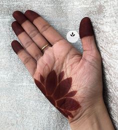 a person's hand with brown leaves painted on it and a white towel in the background