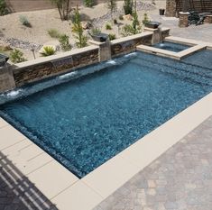 an empty swimming pool in the middle of a patio with stone walls and steps leading up to it