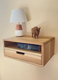 a wooden shelf with a lamp and book on it next to a small animal figurine