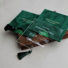 two green business cards with tassels on top of each other, sitting next to each other