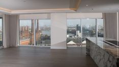 an empty living room with large windows overlooking the city