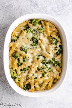 a white bowl filled with pasta and broccoli on top of a gray surface